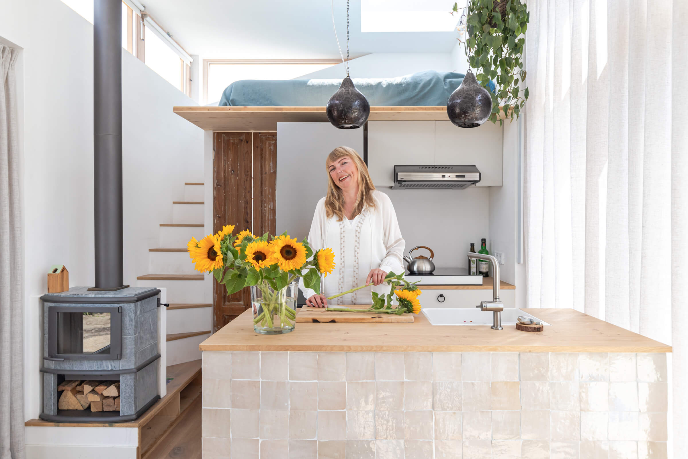 Een foto van Marjolein Jonker achter een kookeiland in haar lichte tiny house.